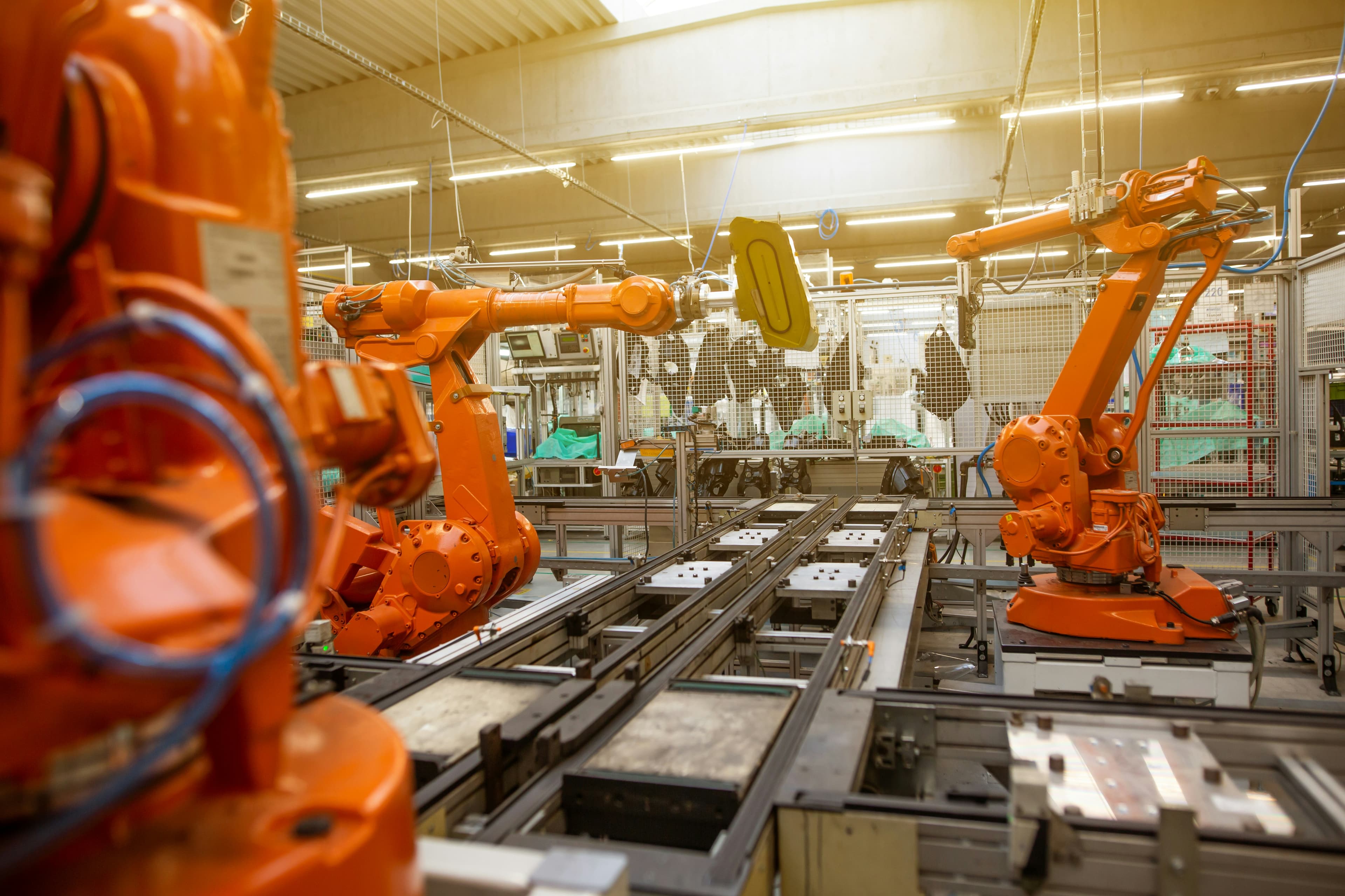 Orange robot arms along an automated production line with pallet conveyors.